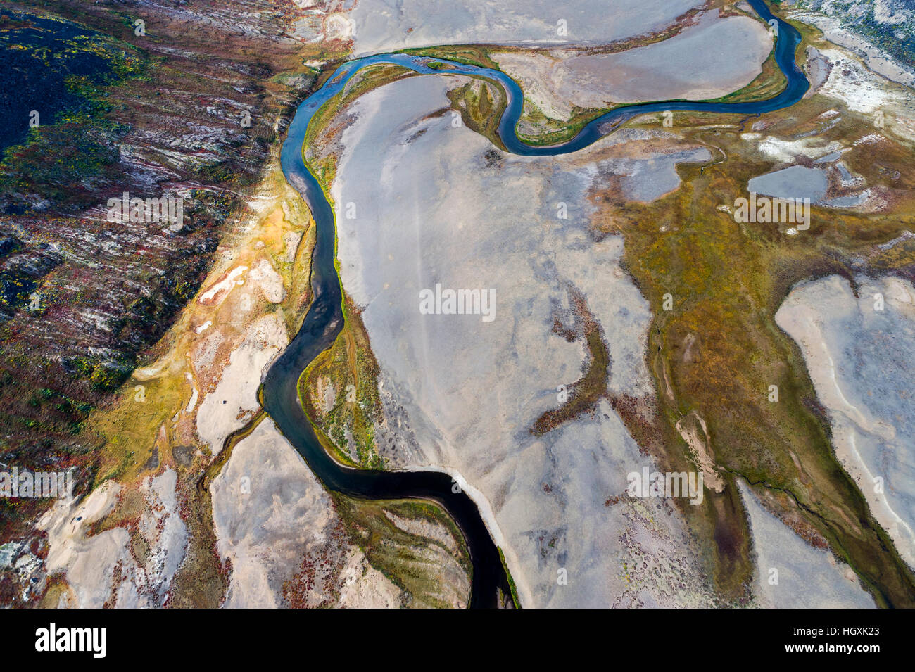 A winding river snakes it's way across a highland tundra valley floor ...