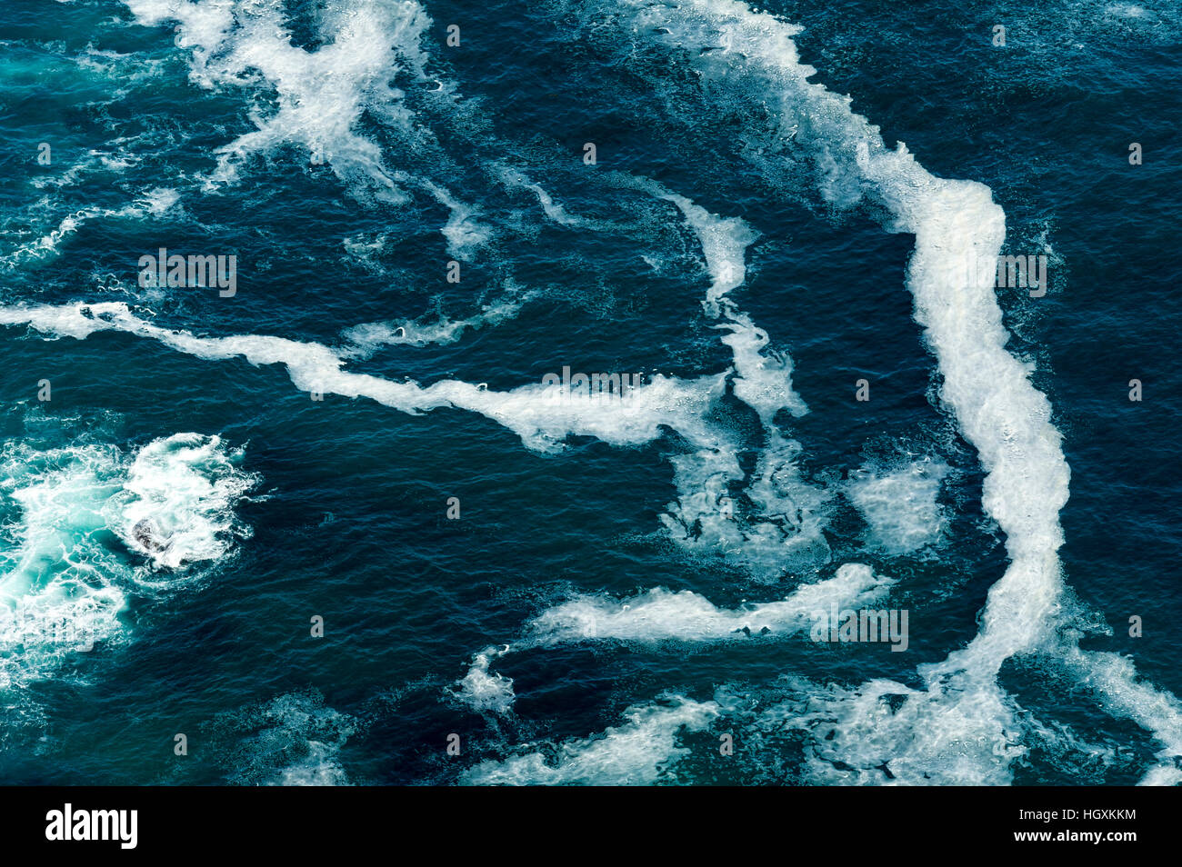 Wave foam trapped in currents along the base of coastal cliffs. Stock Photo