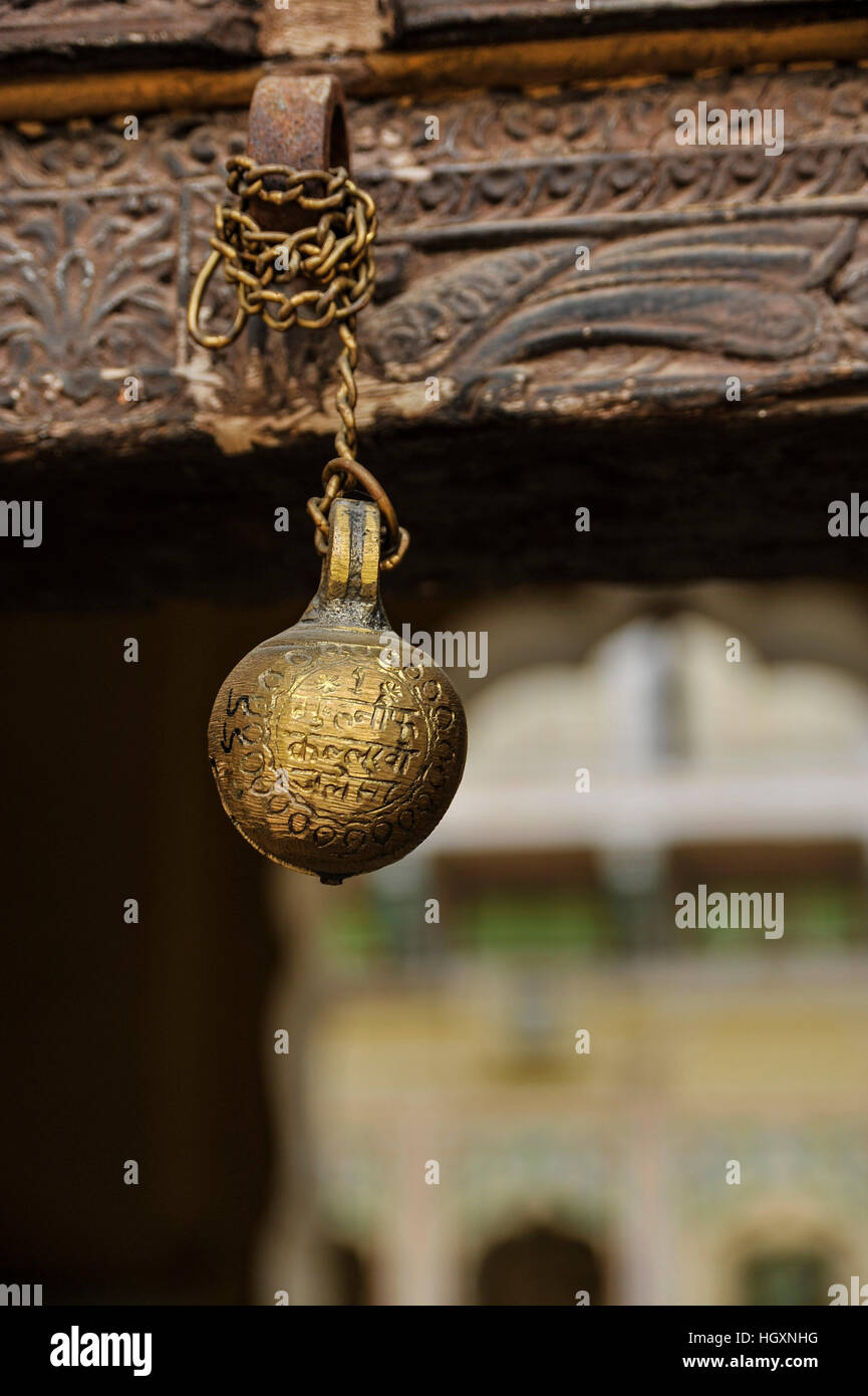 A cowbell / goatbell hung from a carved door-frame in Rajasthan Stock Photo