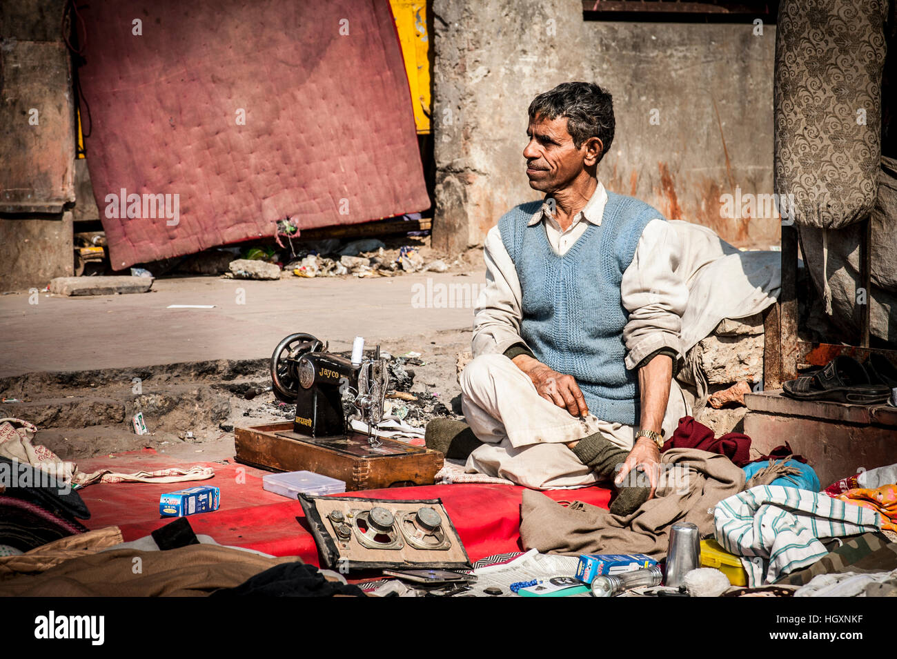 Street hawker / repairman with sewing machine and wares in slum near Jama Masjid, Delhi Stock Photo