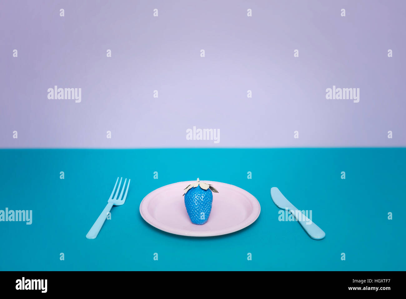 Creative blue strawberry on a plate with fork and knife Stock Photo