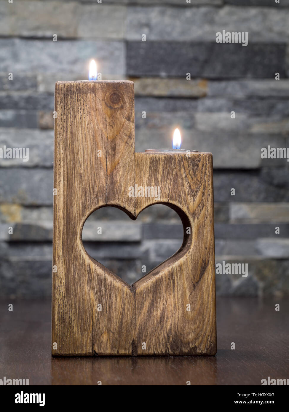 Lit romantic wooden candle holder with cut heart Stock Photo