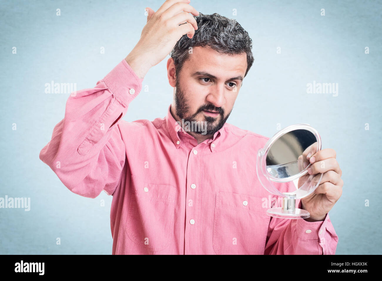 Man worried about gray hair looking in a mirror Stock Photo