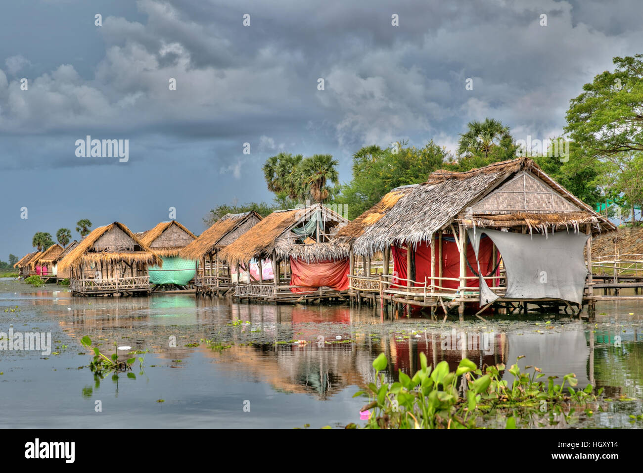 This idyllic scene was taken of a few houses on stilts reflected in Tonl (lake) Bati, Phnom Penh, Cambodia. Stock Photo