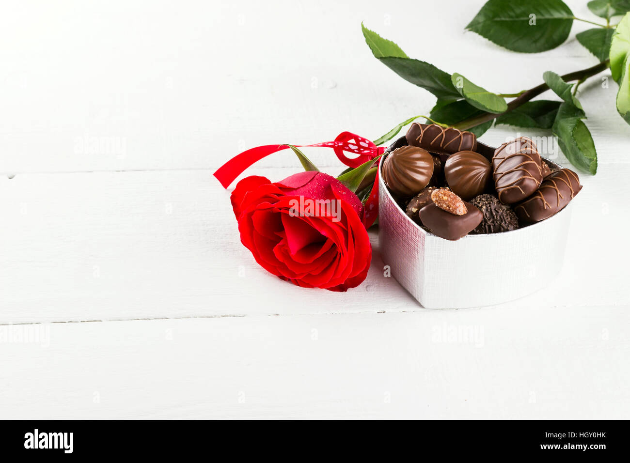 Red rose, box of chocolates on a white wooden background Stock Photo