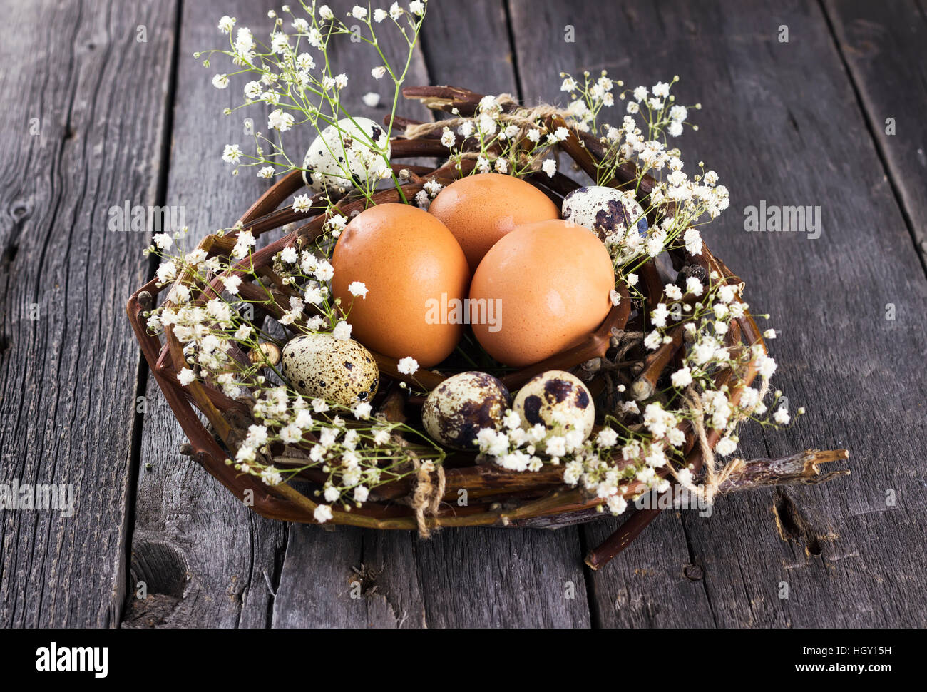 Eggs in nest decorated with flowers against dark background Stock Photo ...