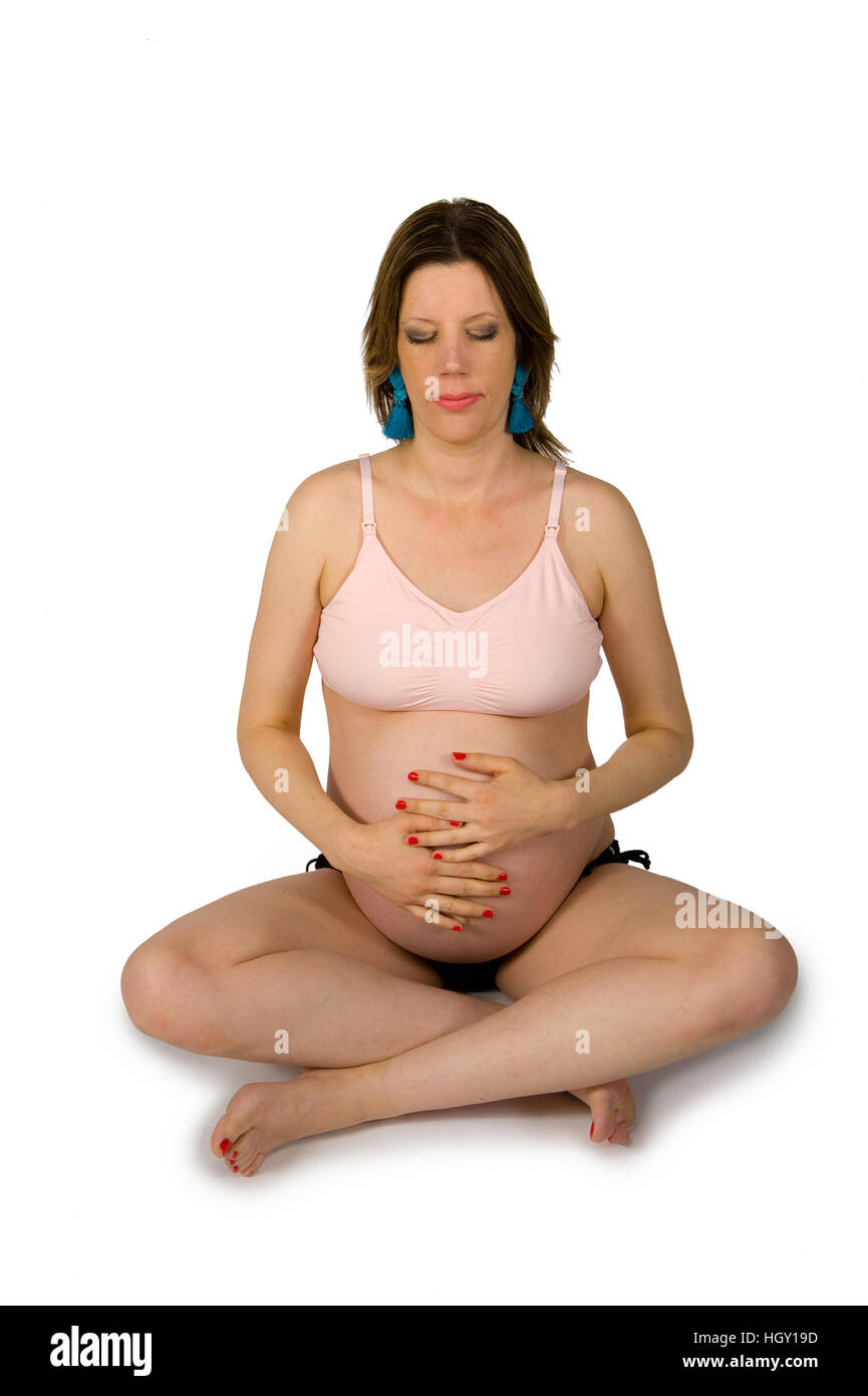 Pregnant woman is concentrating and holding her belly in a yoga sit Stock Photo