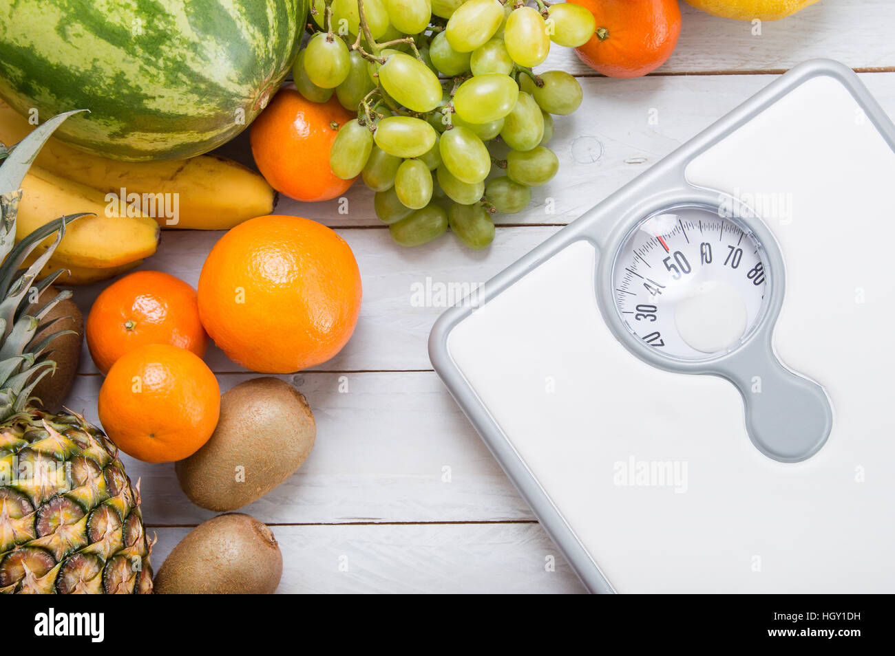 Stack of fruits and white weight scale on wooden board. Concept of diet and healthy lifestyle Stock Photo