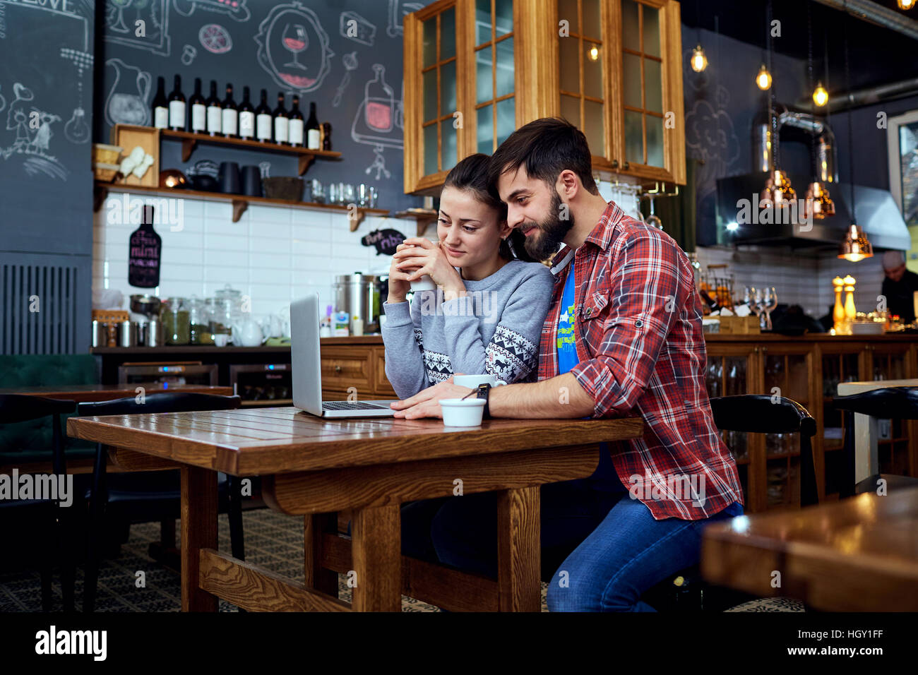 Young couple reading, looking at a laptop in  cafe Stock Photo
