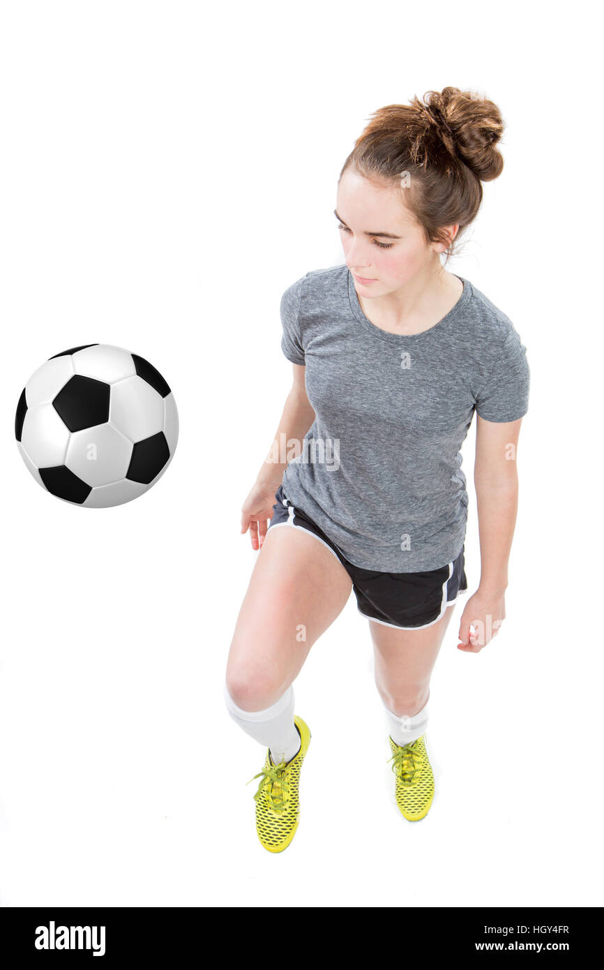 Teenage girl wearing soccer cleats and shin guards dribbling a soccer