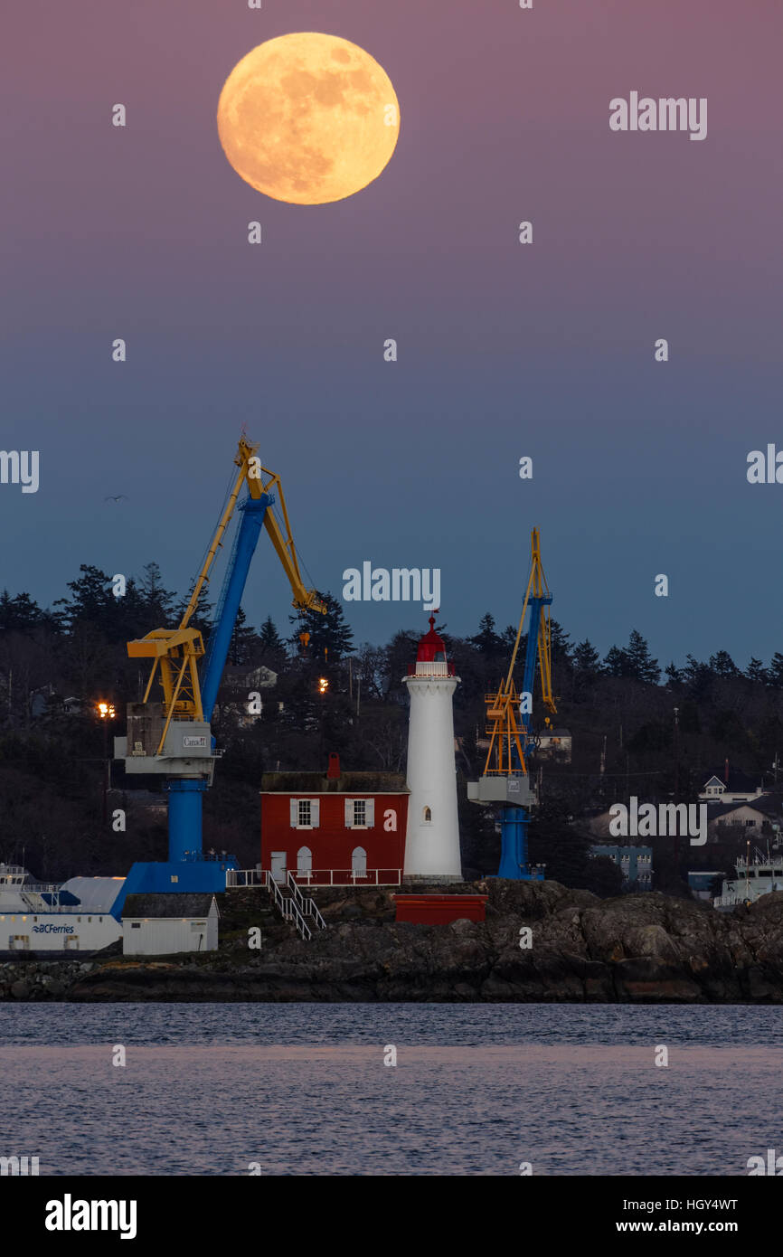 Full moon rising over Fisgard lighthouse and Esquimalt dockyard-Esquimalt, British Columbia, Canada. Stock Photo