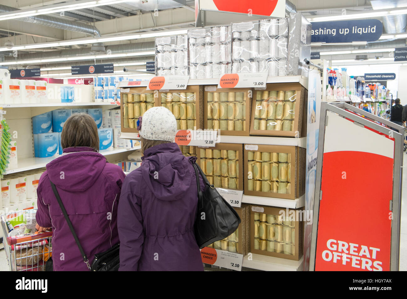 two ladies shopping for gold coloured christmas crackers in a