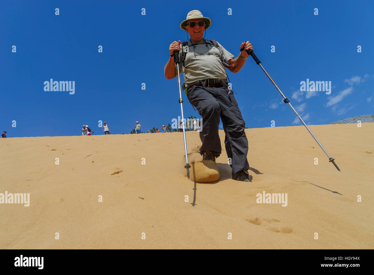 Close up of a senior man with walking poles running down the almost 49 metres high sand dune at  Salir do Porto, Portugal Stock Photo