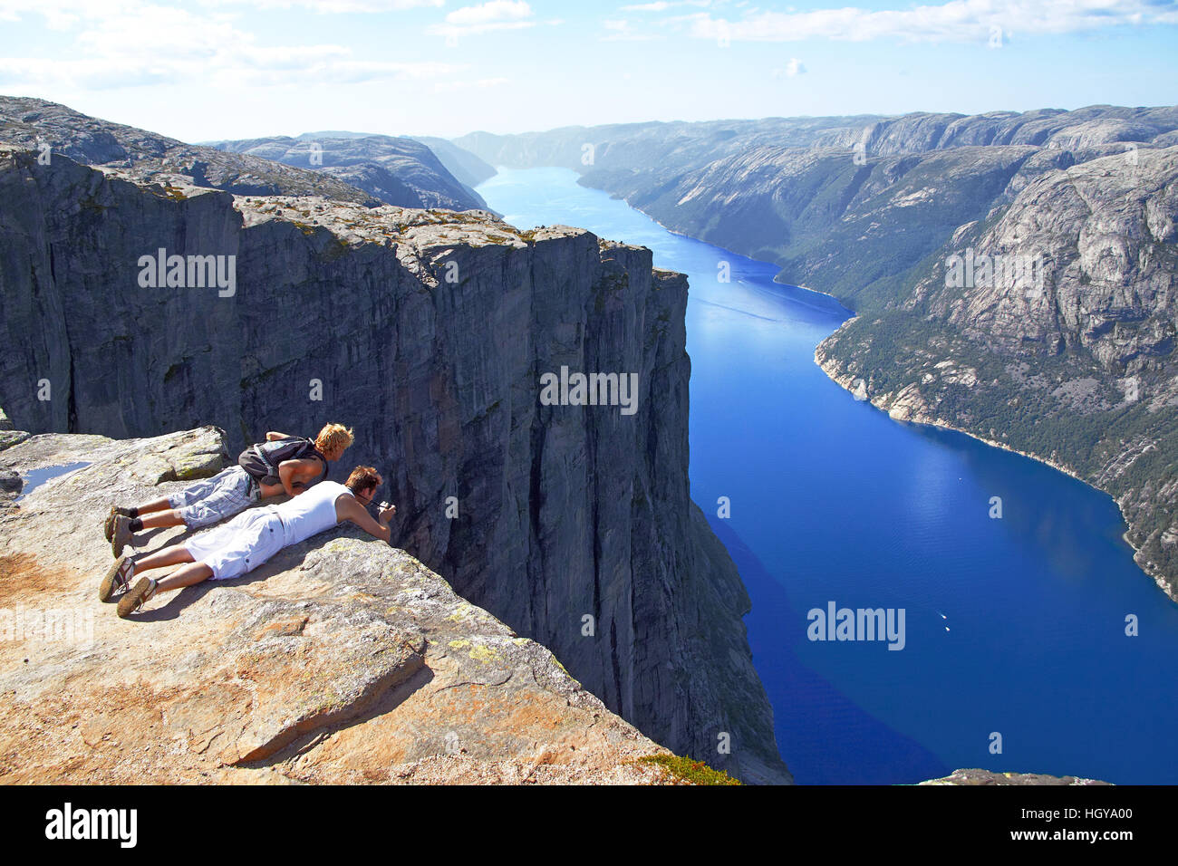 KJERAGBOLTEN, NORWAY - JUNE 23, 2015: tourists are on the edge of the cliff and photograph the majestic fjord in Kjeragbolten  mountains,  Norway Stock Photo