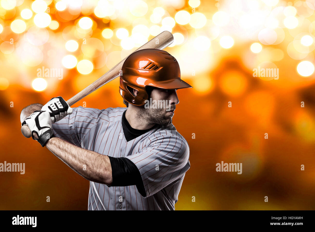 baseball-player-on-a-orange-uniform-on-orange-lights-background-stock