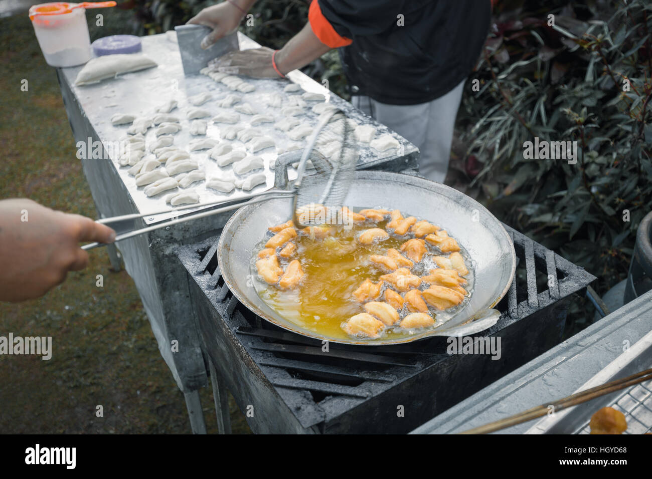 Frying deep fried dough sticks in pan of hot cooking oil. Chef cooking and prepare white raw flour on table beside. Stock Photo