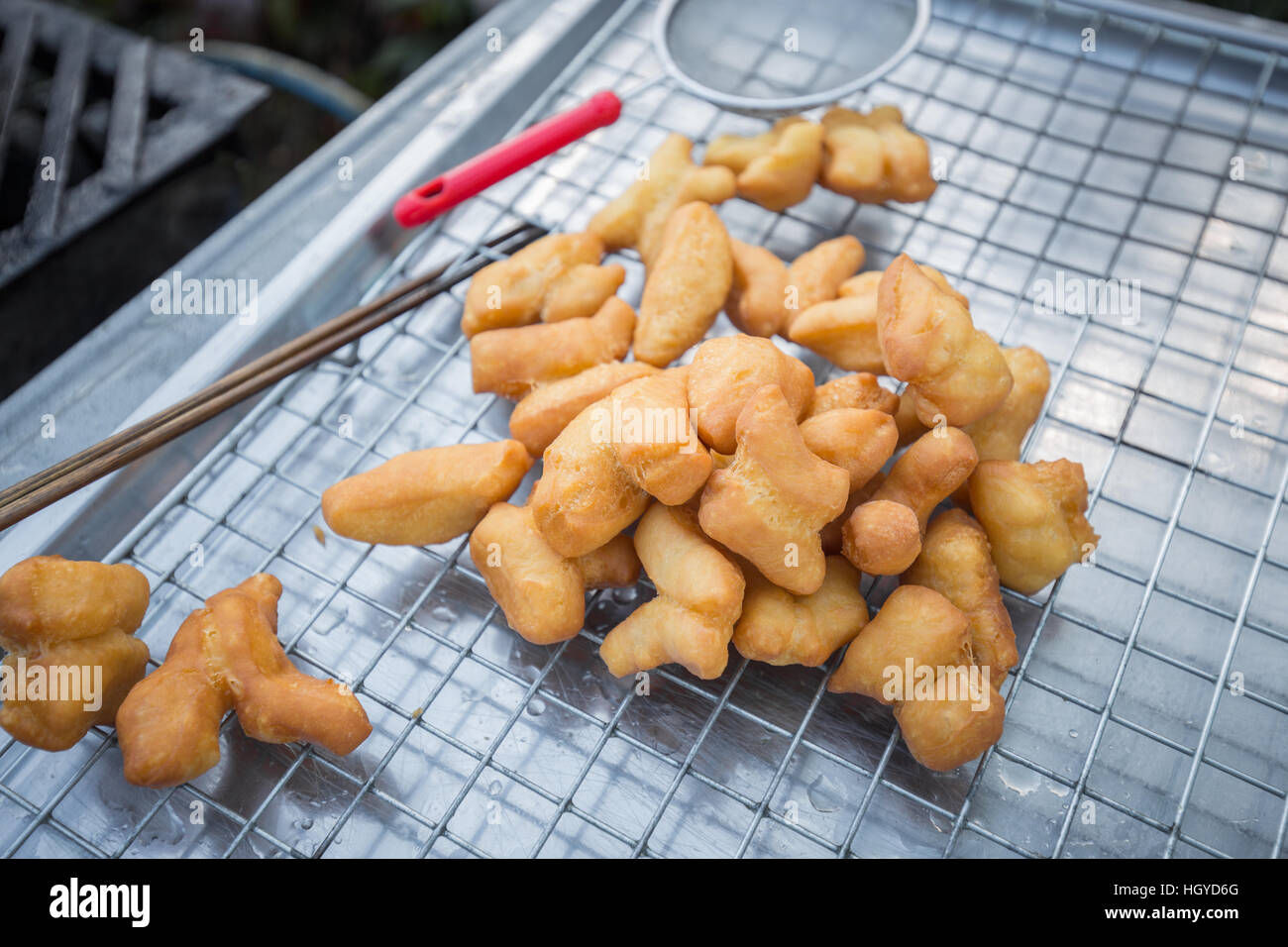 Close focus on deep fried dough stick put on grille of stainless steel tray for preparing to serve. Stock Photo