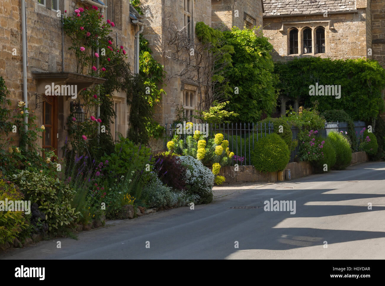 Cotswold stone cottages with colourful roadside floral borders in the village of Stanton, Cotswolds, Gloucestershire, England Stock Photo