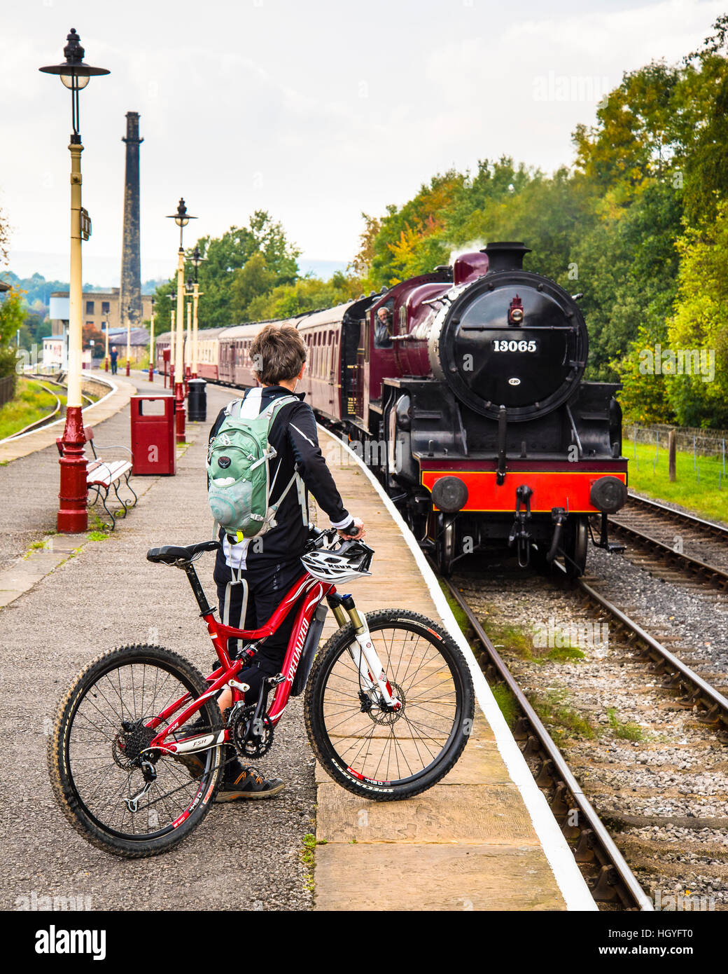 Woman with bicycle as steam train approaches at Rawtenstall on the East Lancashire Railway Stock Photo