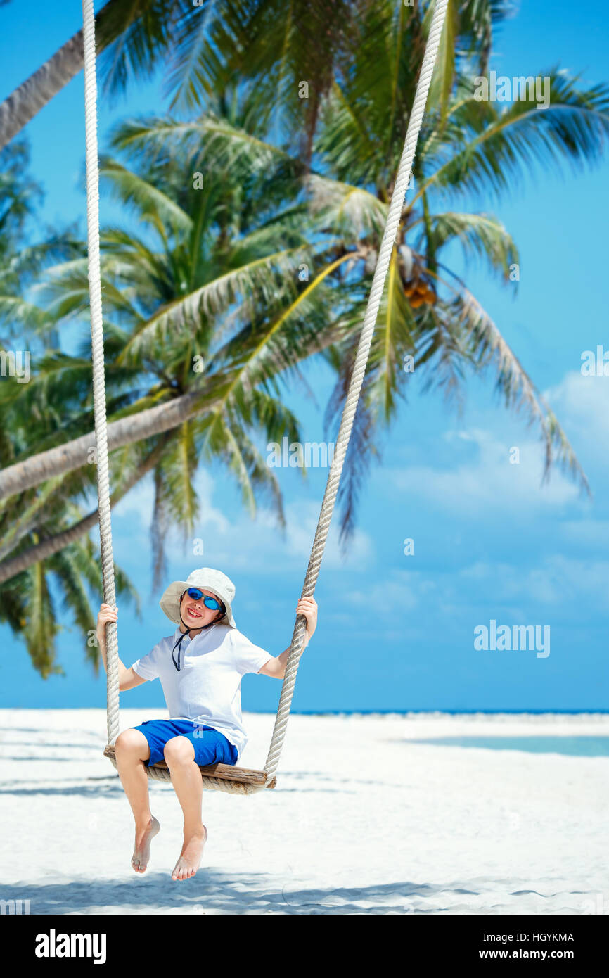 Cute boy having fun swinging at tropical island beach Stock Photo