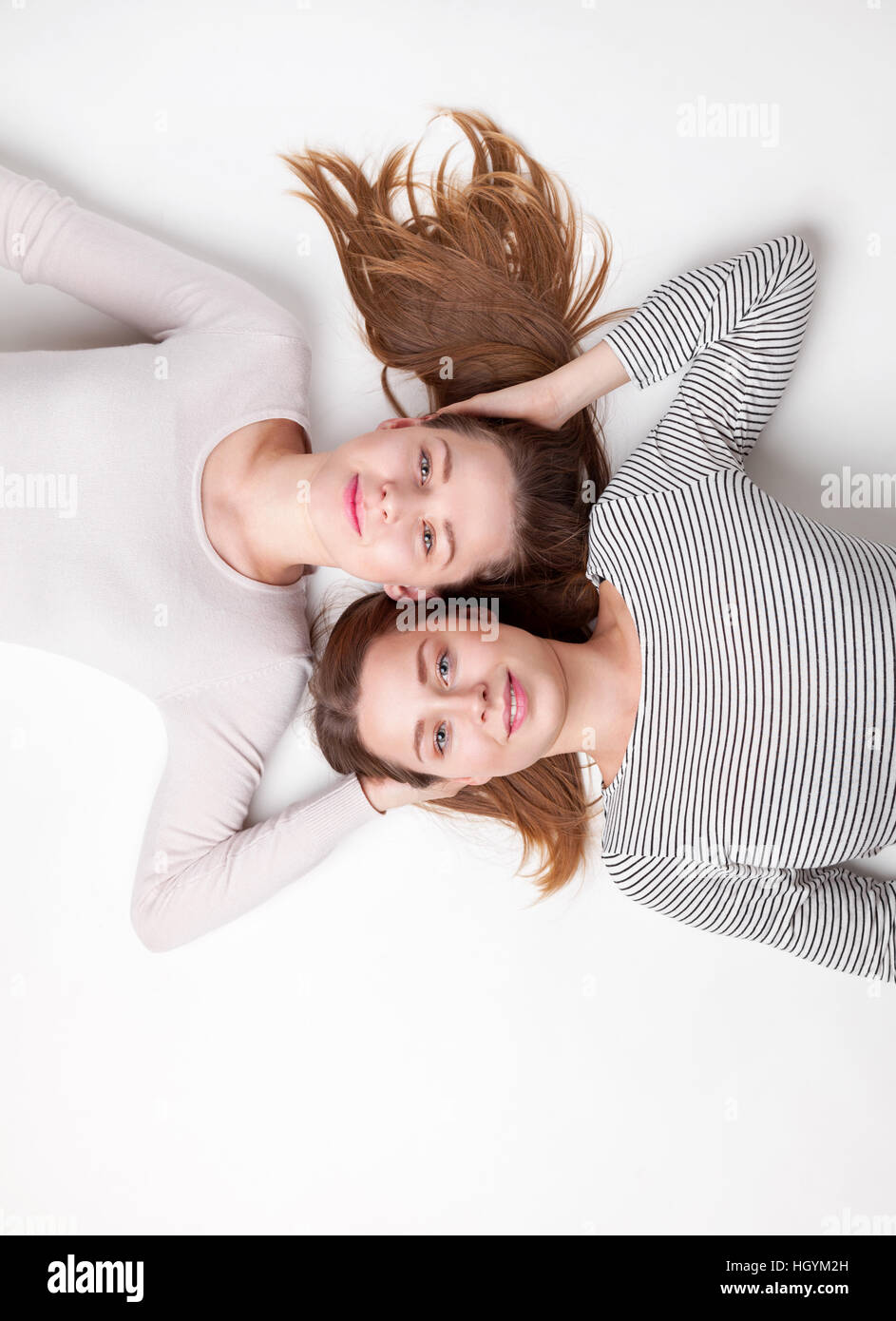 Portrait of young and happy sisters lying on the floor Stock Photo