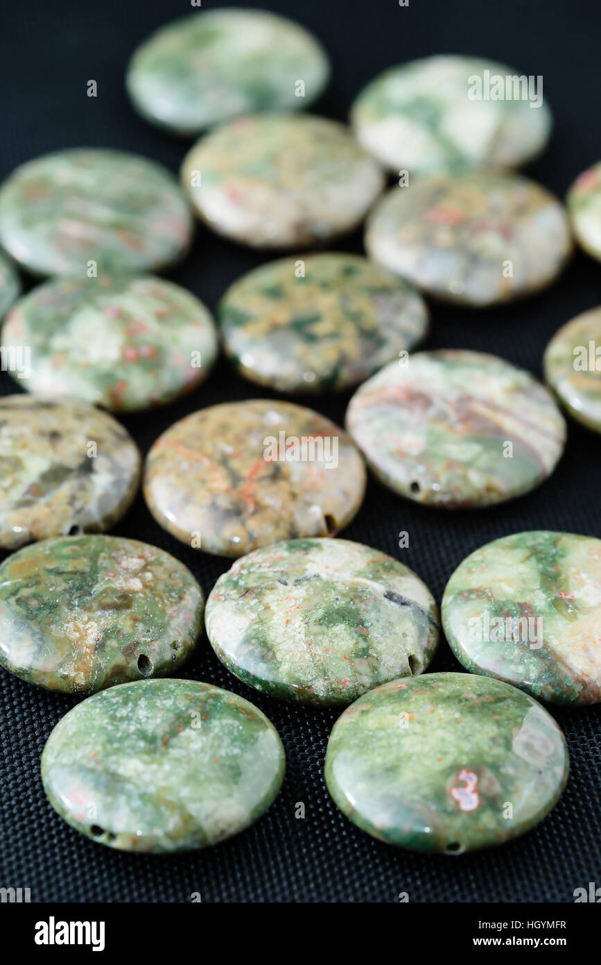 Green marbled agate coin shaped beads on black weave. Stock Photo