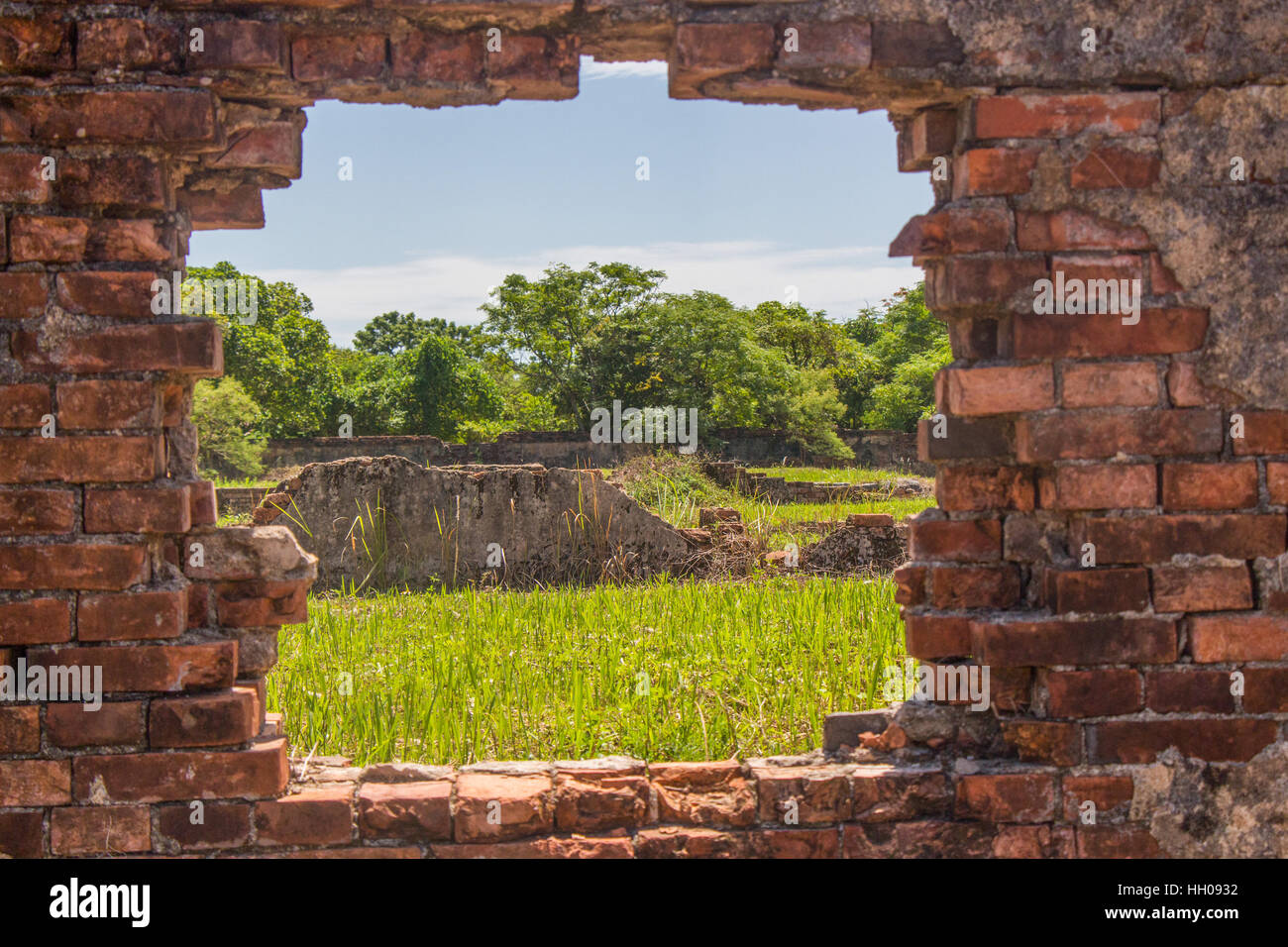 Looking out through the weathered decaying window at overgrown ruins. Imperial Citadel, Hue, Vietnam Stock Photo