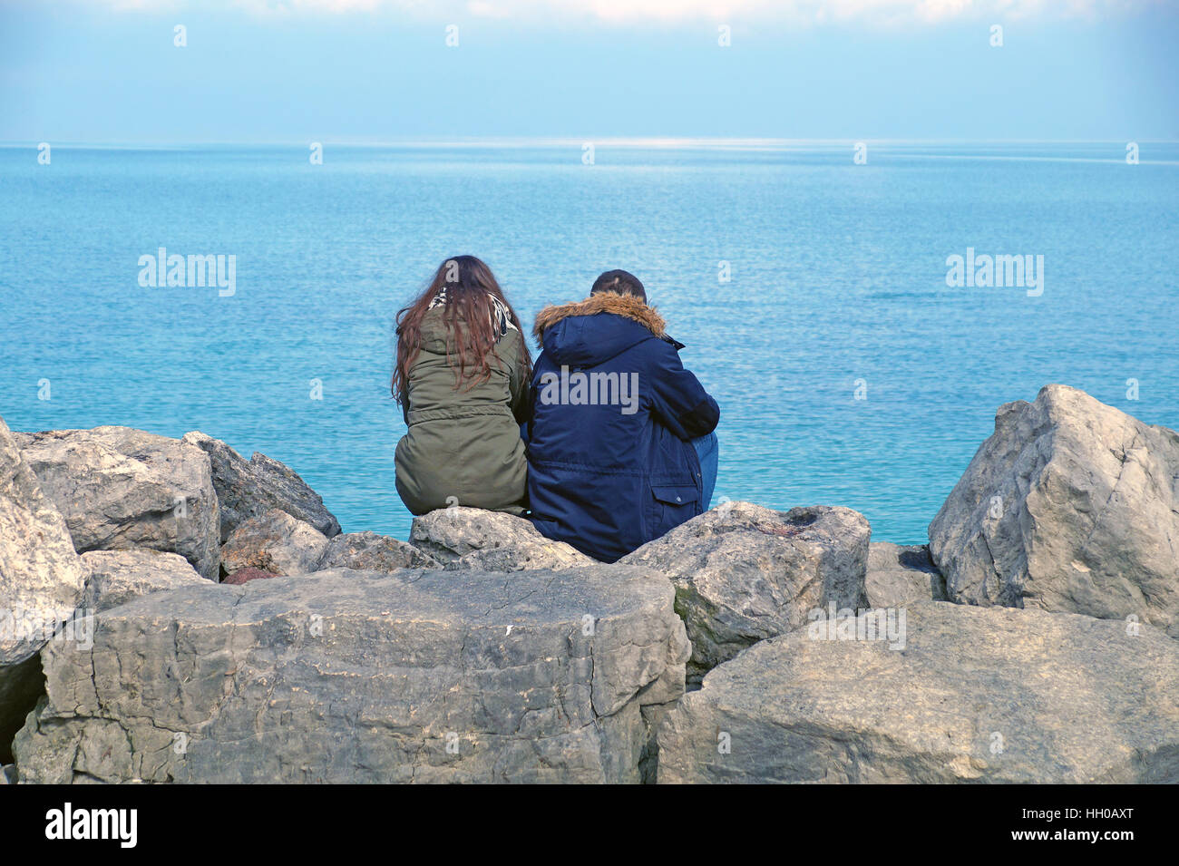 people sitting on the rocks watching the horizon Stock Photo