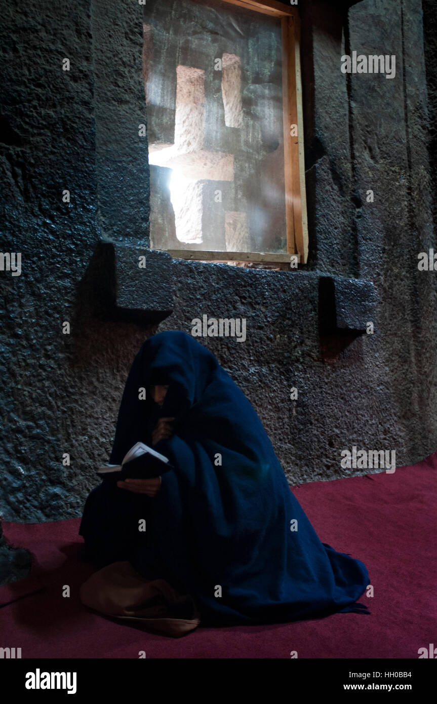 Lalibela, Amhara region, Ethiopia. A woman prays inside the church Bet Medhane Alem. To admire the churches of Lalibela one does not have to look upwa Stock Photo