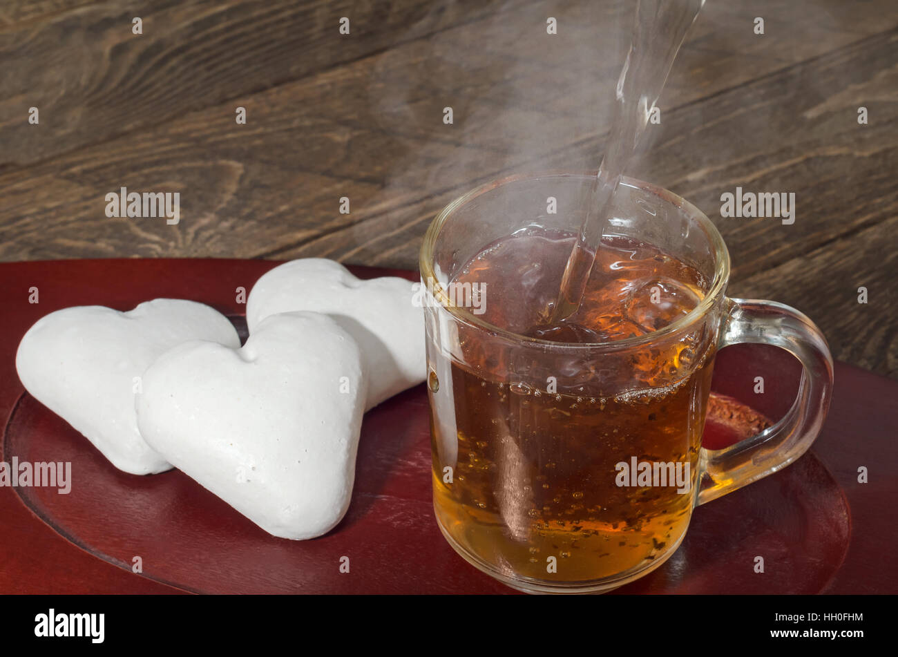 Ginger cookies in the shape of a heart and hot tea poured. Low key, selective focus. Stock Photo