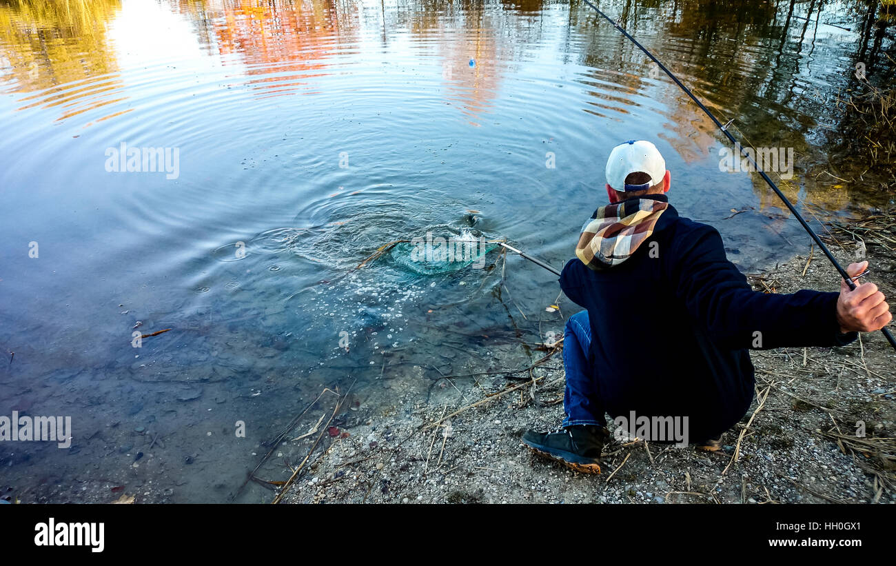 Fisherman with fishing rod and landing net during pulling out Stock Photo