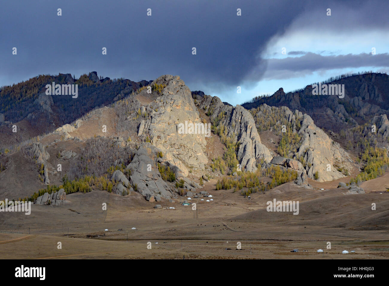Mongolian steppe landscape on the Trans Siberian Railway with storm clouds on the horizon and traditional gerts dwarfed in the foreground Stock Photo