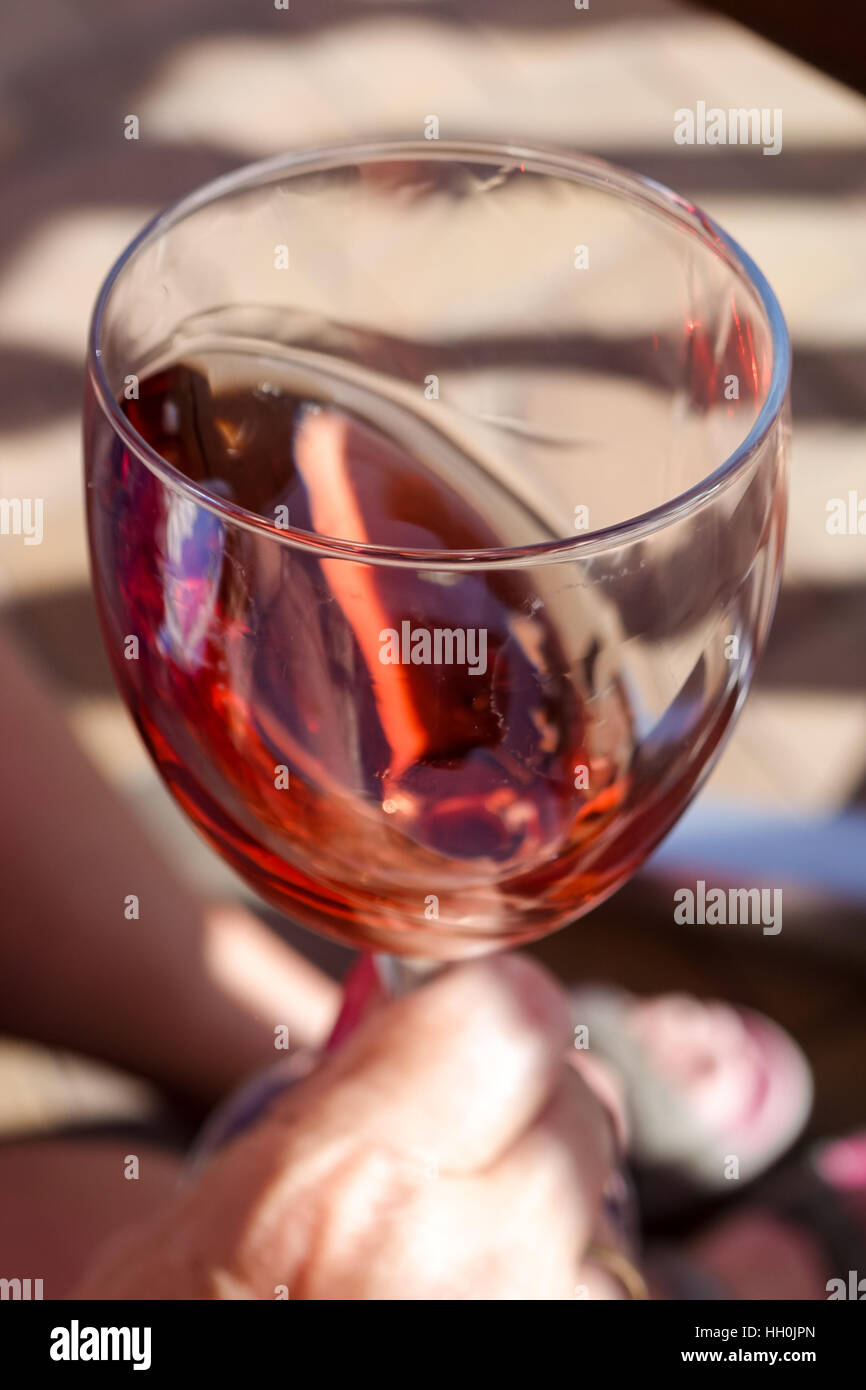 Glass of Rose wine being swirled with hand in shot Stock Photo