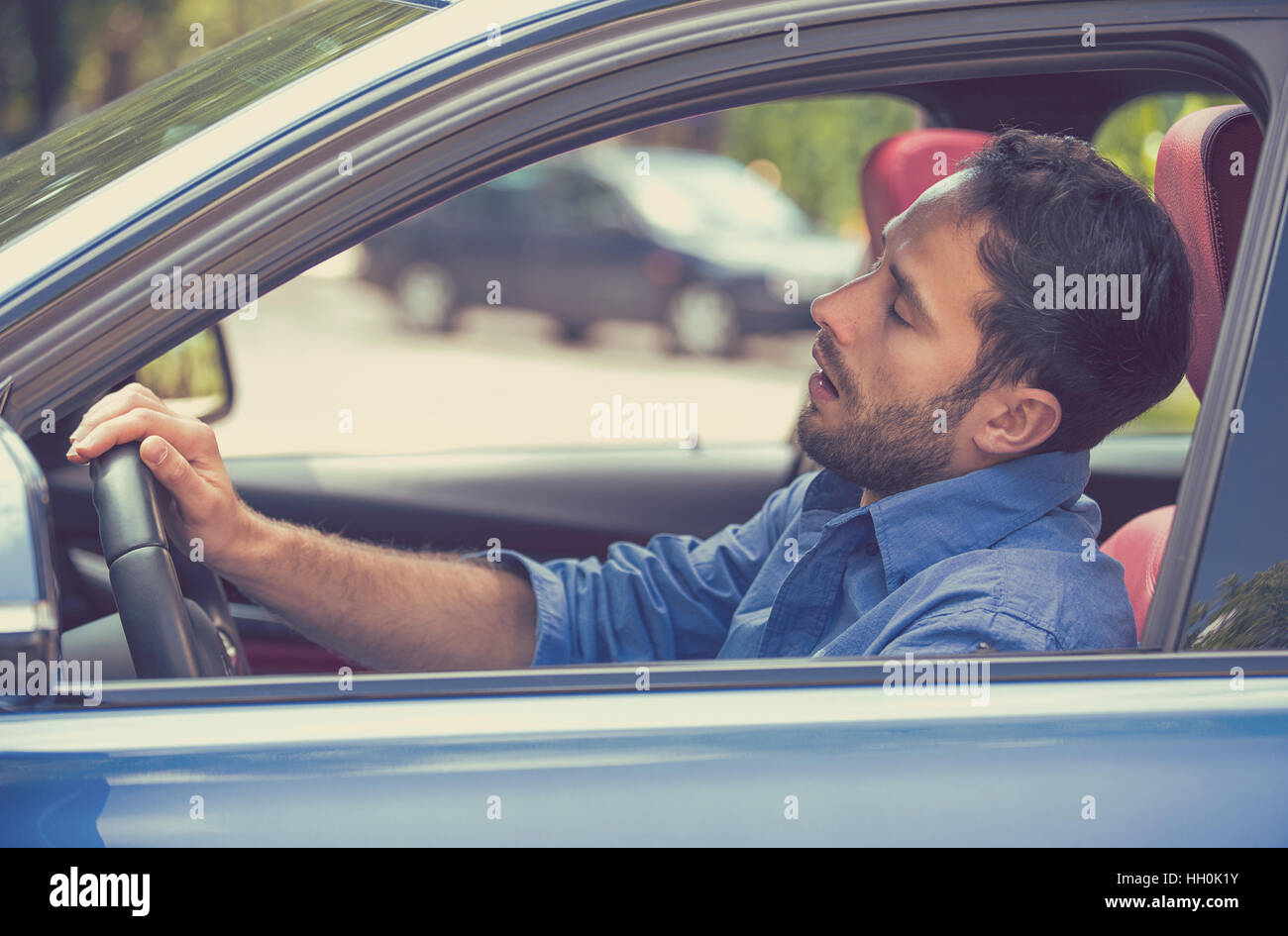 Side view sleepy tired fatigued exhausted man driving car in traffic after long hours. Transportation safety sleep deprivation Stock Photo