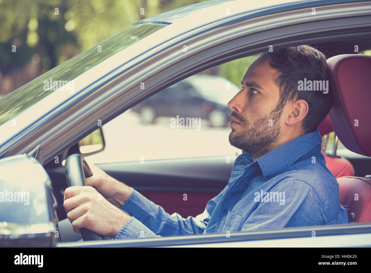 scared funny looking young man driver in the car. Human emotion face expression. Side window view of inexperienced anxious motorist Stock Photo