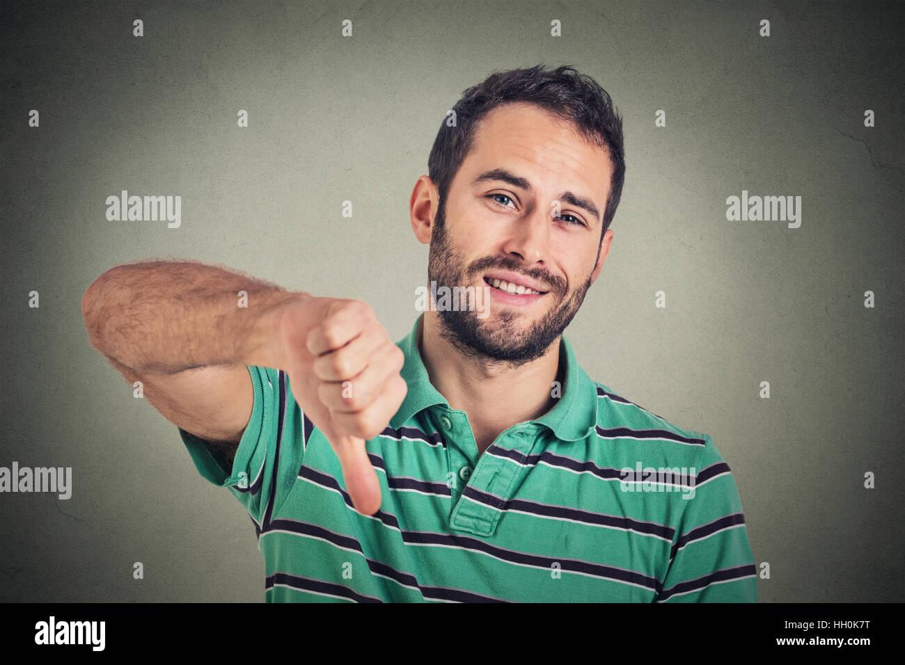 sarcastic young man showing thumbs down sign hand gesture, happy someone made mistake, lost, failed isolated on gray background Stock Photo