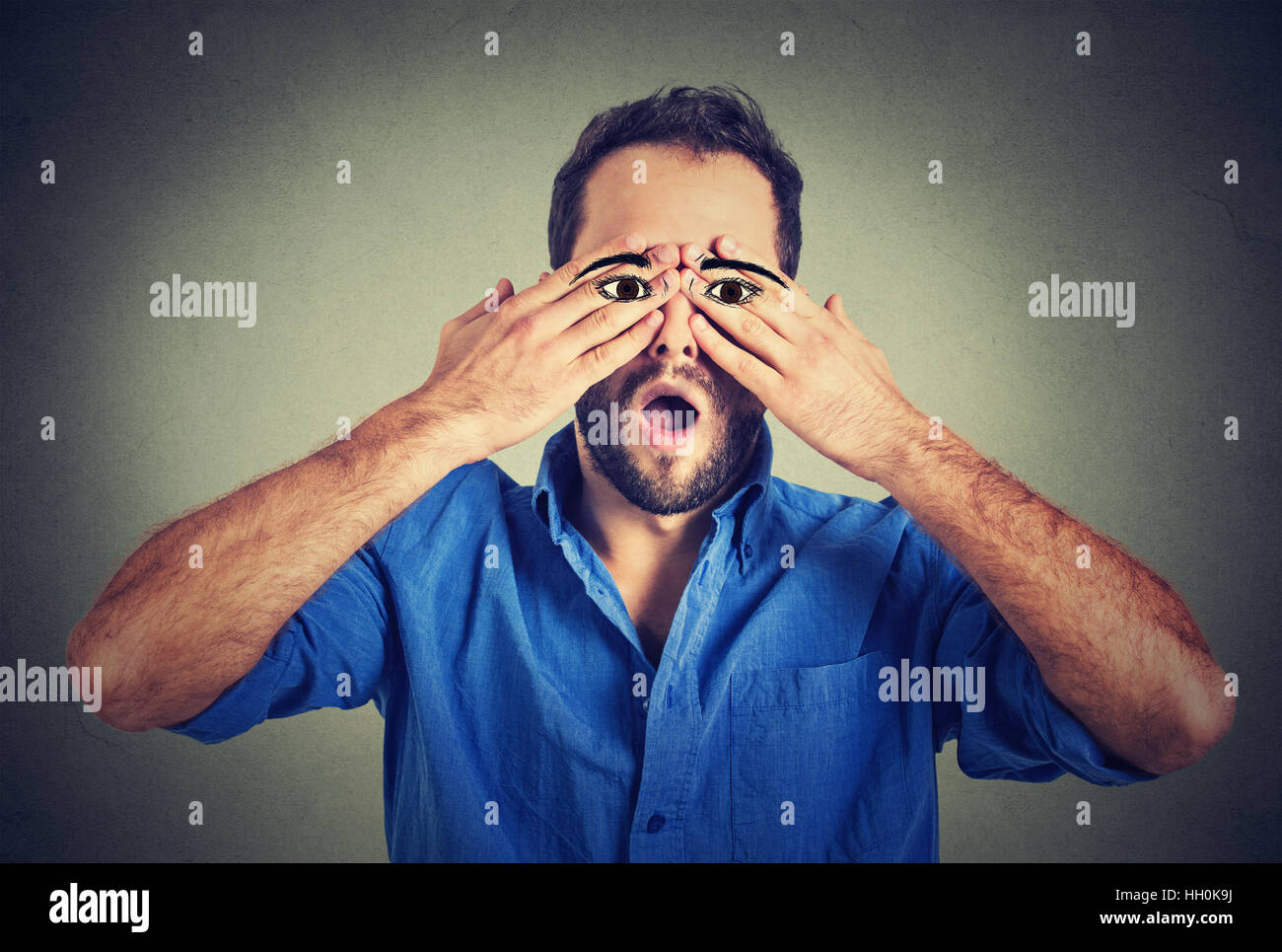Surprised handsome man with eyes painted on his hands Stock Photo - Alamy