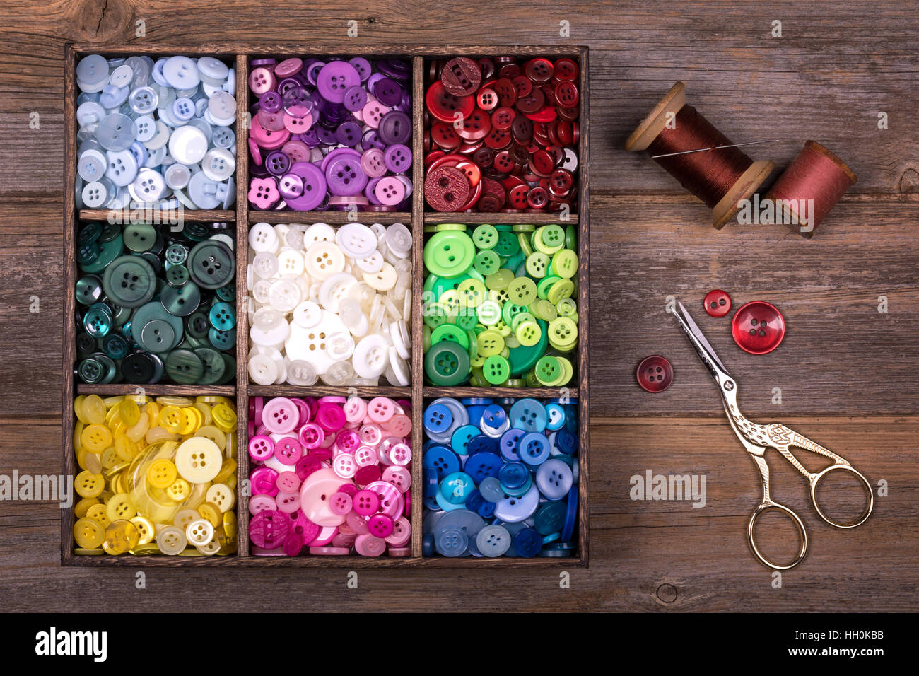 A box of colourful buttons, sorted into colour groups, in an old wood ...
