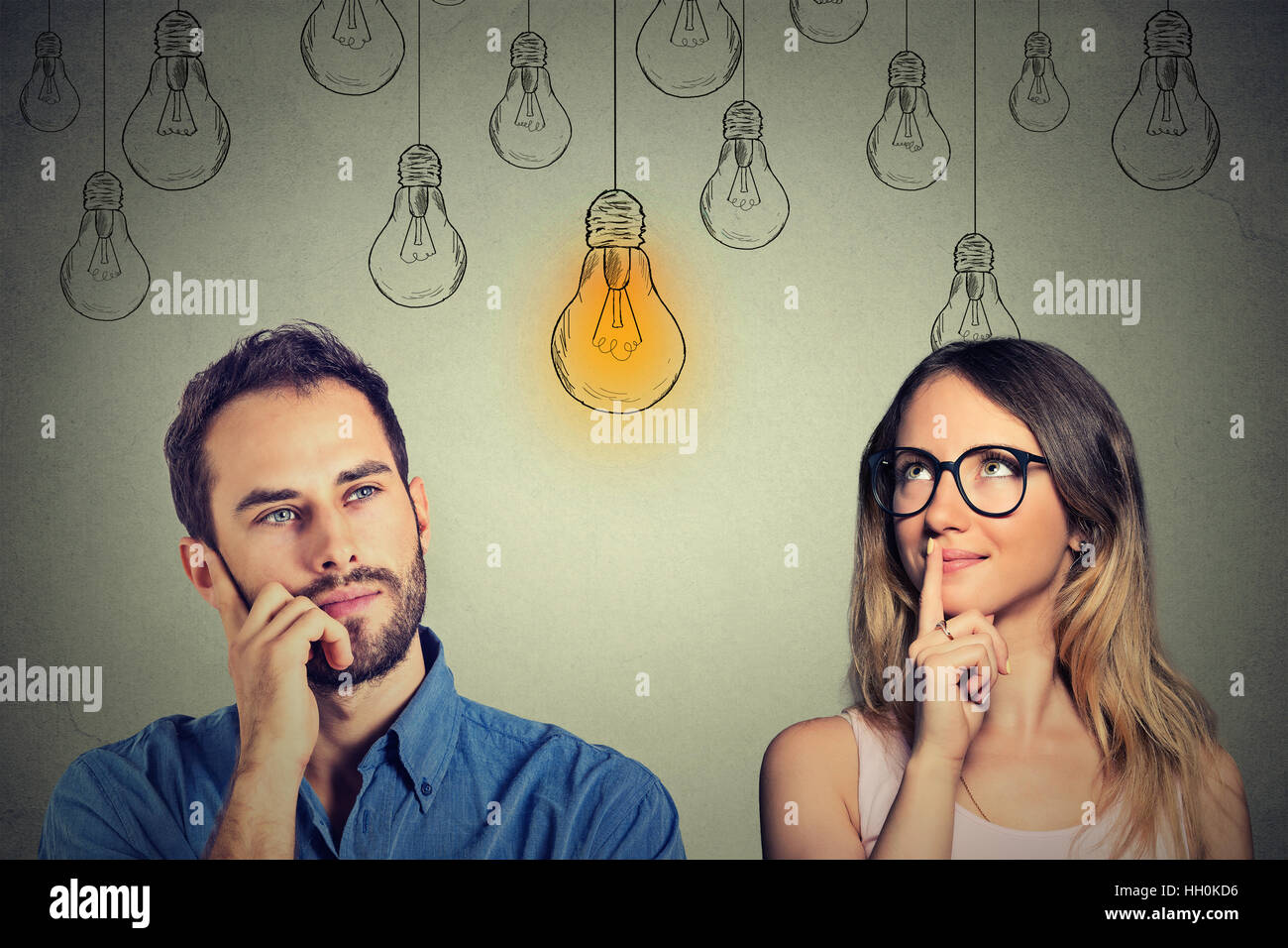 Cognitive skills ability concept, male vs female. Young man and woman looking at bright light bulb isolated on gray background Stock Photo