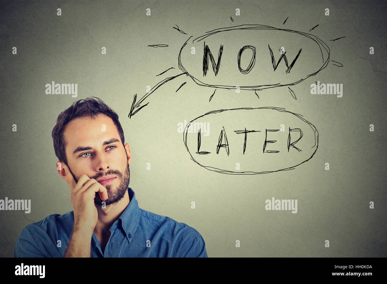 Now or later. Man thinking looking up isolated on gray wall background. Human face expression Stock Photo