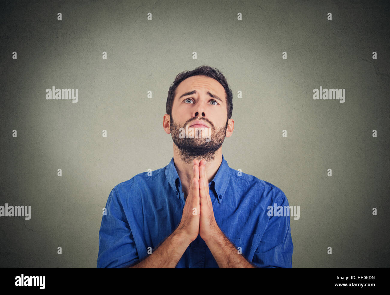 handsome young man praying hands clasped hoping for best asking forgiveness or miracle. Human emotion facial expression feeling Stock Photo