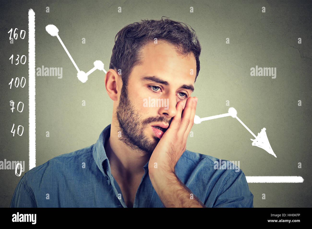 frustrated stressed man desperate with financial market chart graphic going down on gray background. Poor economy financial Stock Photo