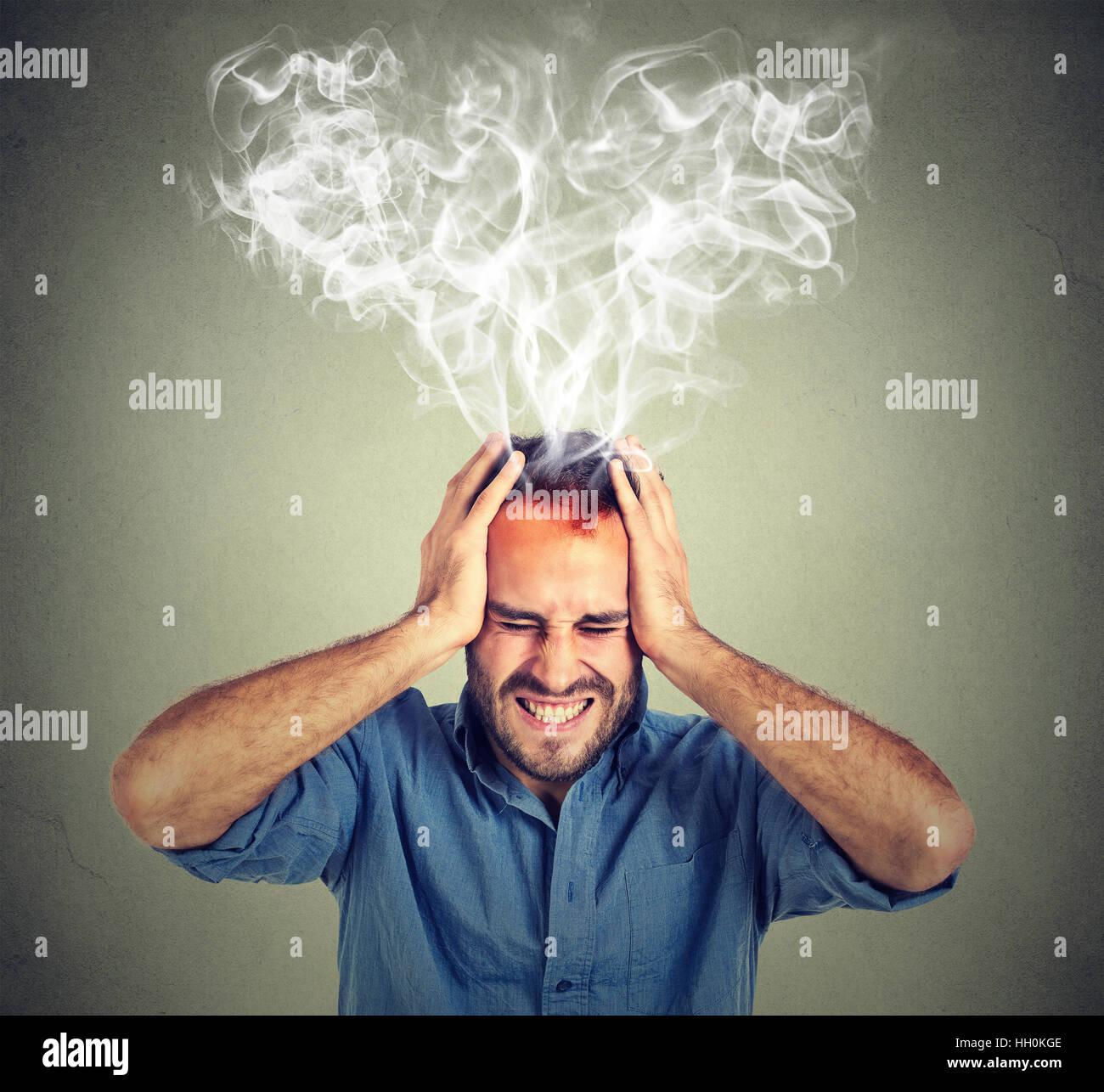 young stressed man screaming thinking too hard steam coming out up of head isolated on gray background. Face expression emotion Stock Photo