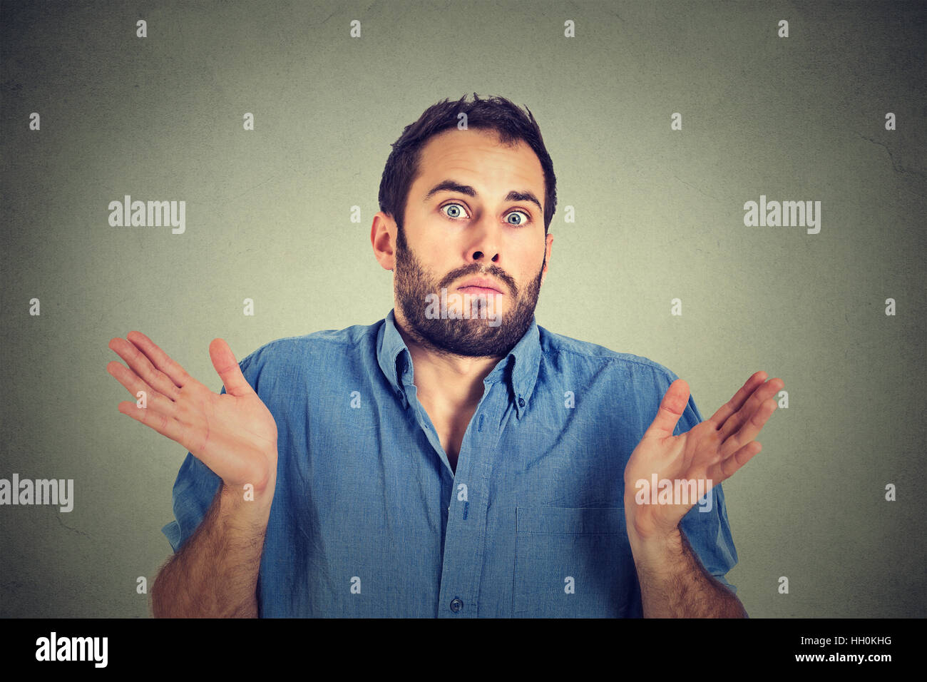 Closeup portrait young man shrugging shoulders who cares so what I don't know gesture isolated on gray background. Body language Stock Photo