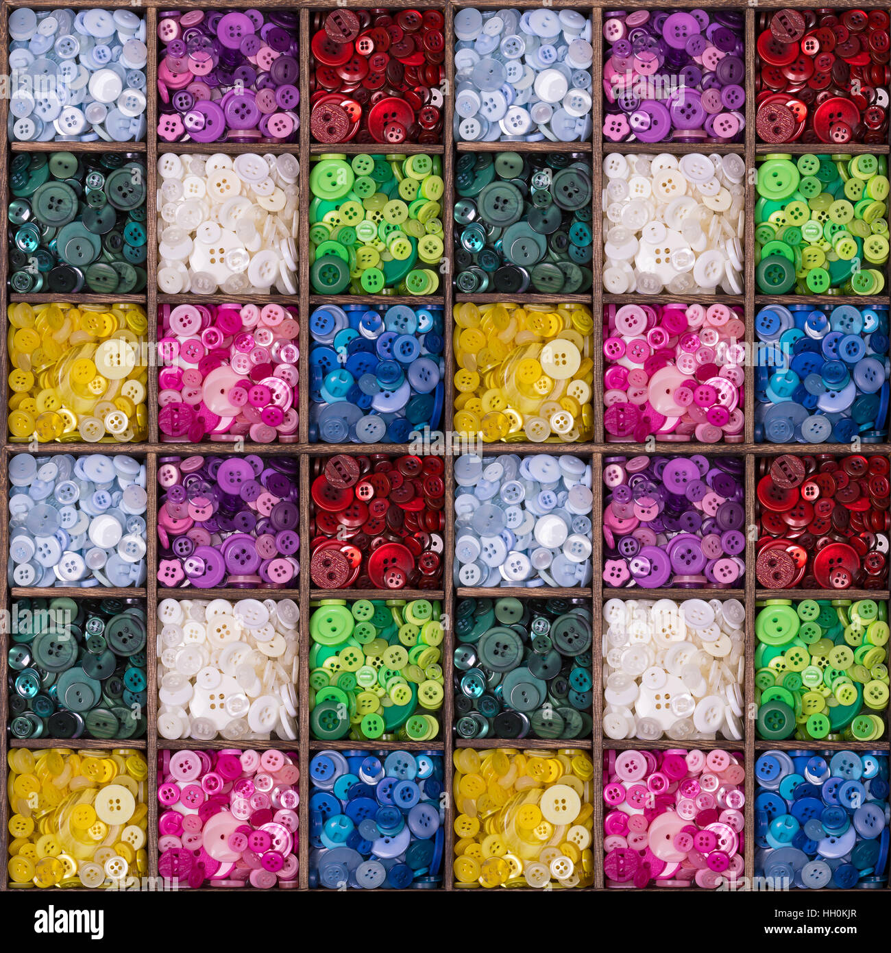 A seamless pattern of colourful buttons displayed in a wooden storage ...