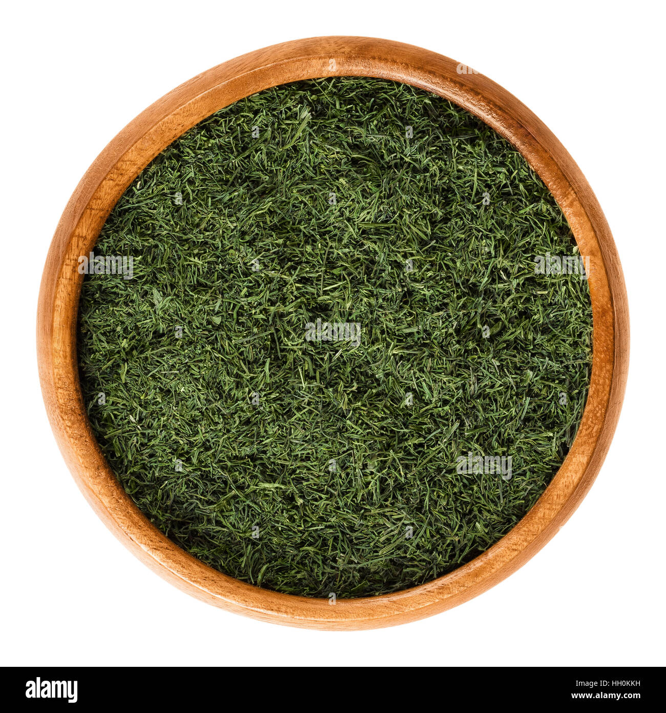 Dried dill fronds in wooden bowl, also called dill weed. Shredded green leaves of Anethum graveolens, used as herb and spice. Stock Photo