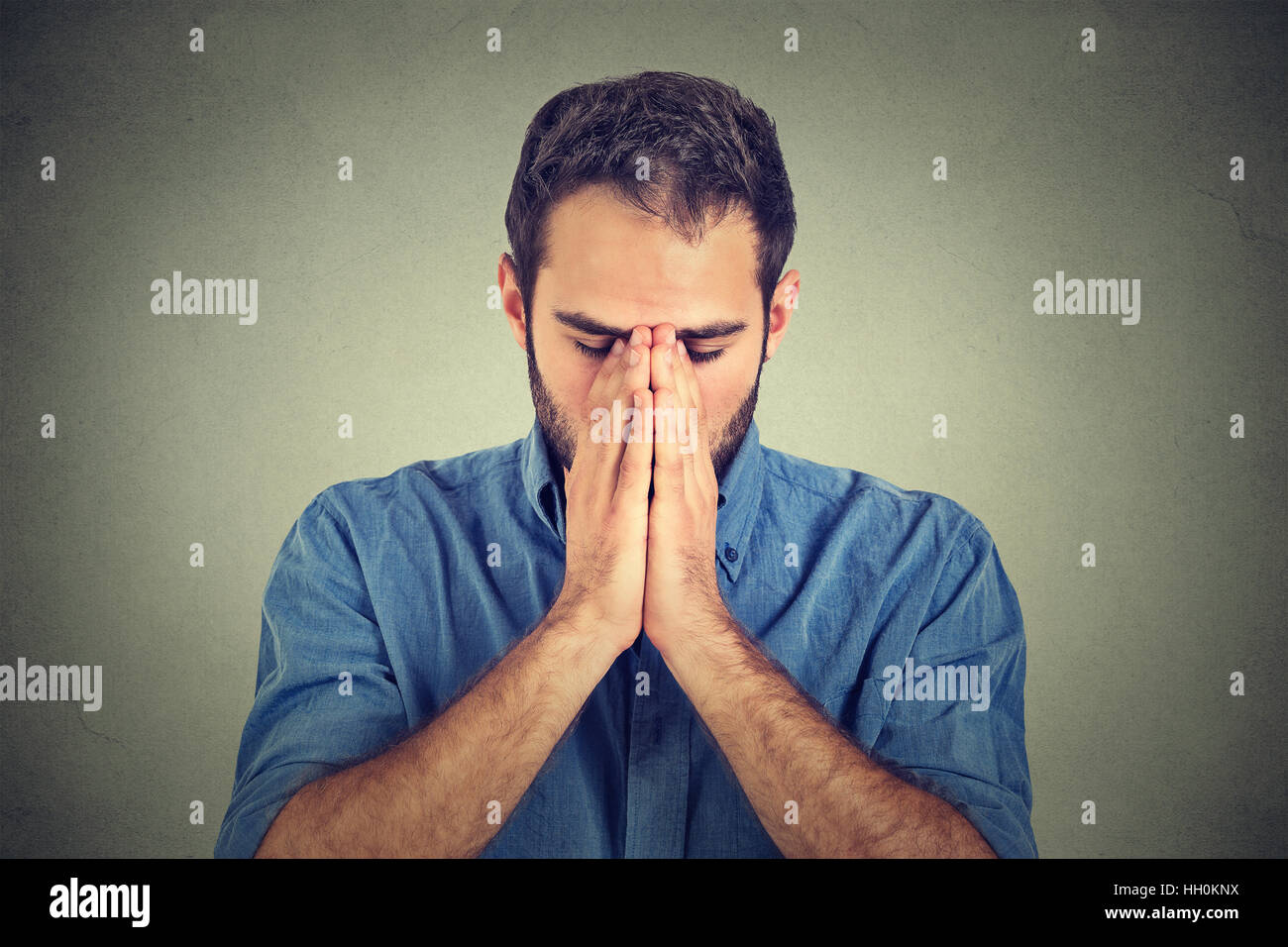 portrait of young desperate sad man isolated on gray wall background Stock Photo