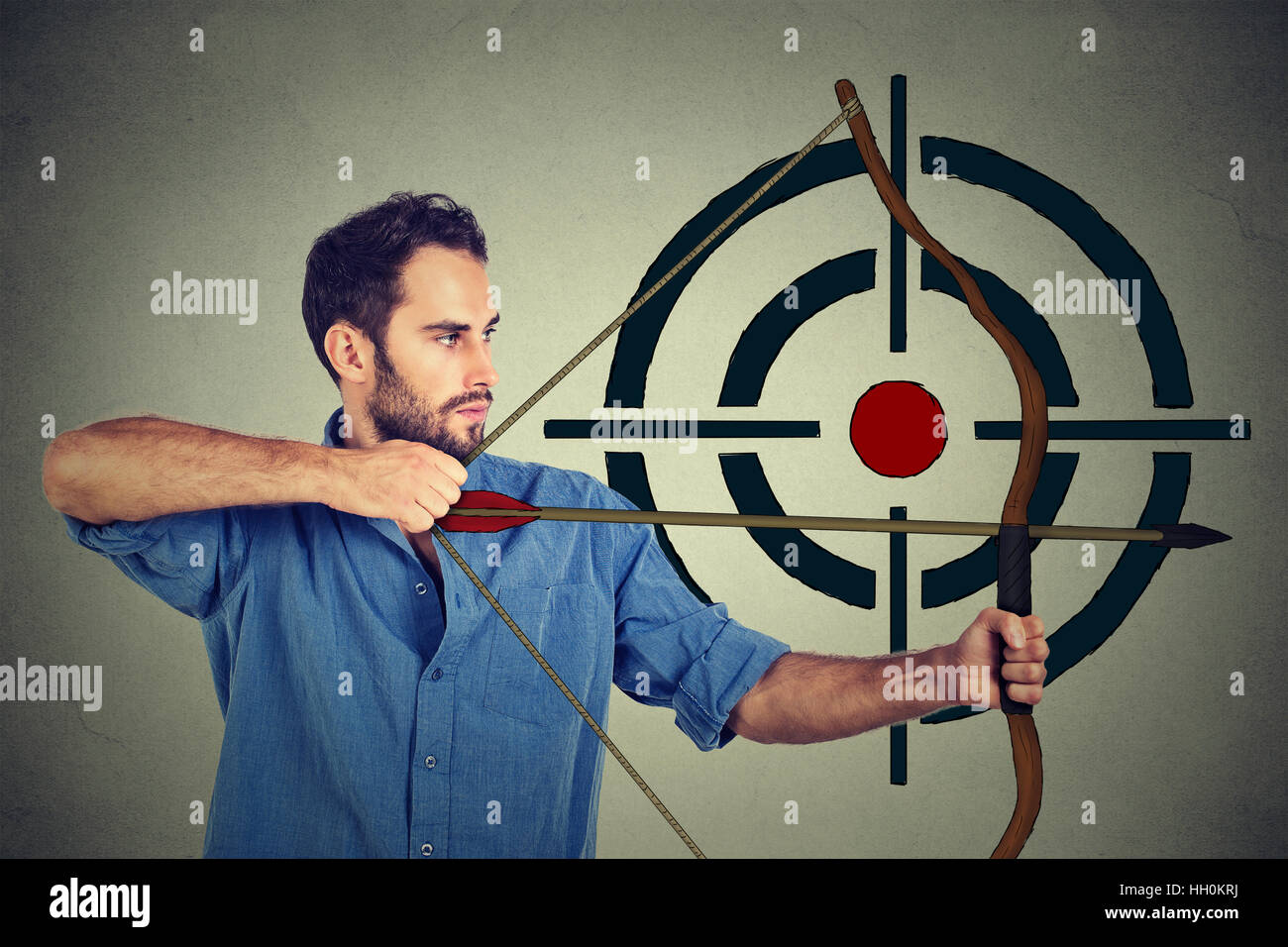 Side profile man trying to hit a target with bow and arrow Stock Photo