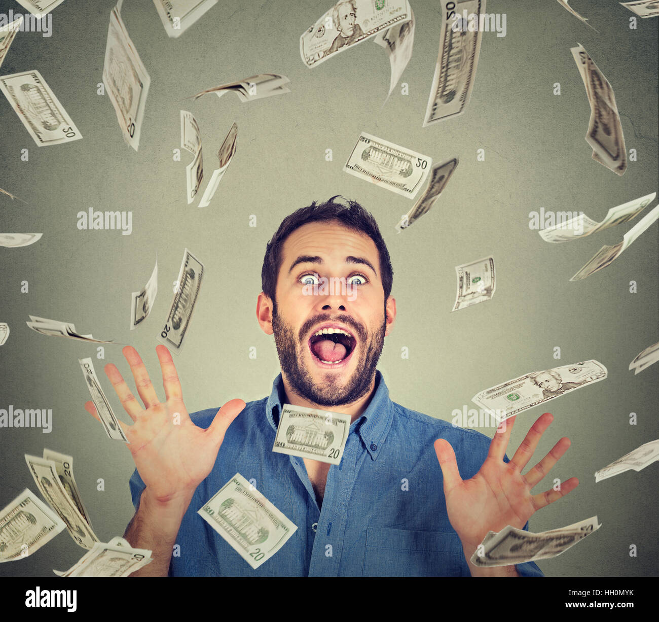 Happy young man going crazy screaming super excited. Portrait ecstatic guy celebrates success under money rain falling down Stock Photo