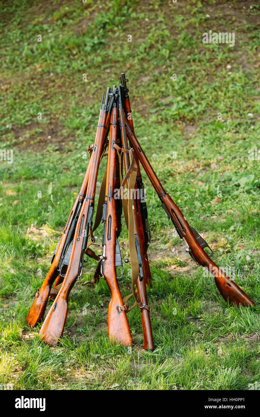 The Rifles Arranged In A Pyramid Shape. The Weapon Installation On Green Grass Background. Stock Photo